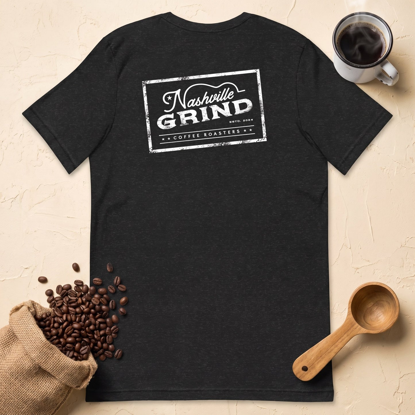 Back of the Nashville Grind Logo Tee laid flat showing the Nashville Grind Coffee Roasters logo, with roasted coffee beans, enamel mug and wooden scoop